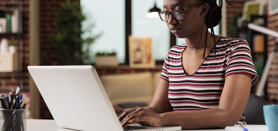 Freelancer working, typing on laptop keyboard, searching information on internet in home office. Employee writing message on computer, copywriting, sitting at workplace desk