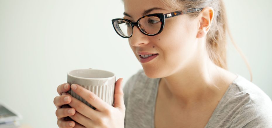 Nerdy girl in glasses drinking coffee while studying at her house