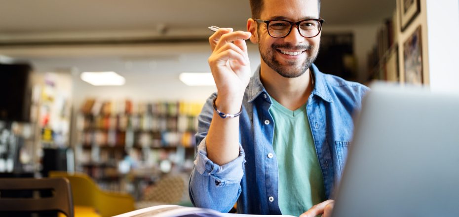 Smiling male student working and learning in a library